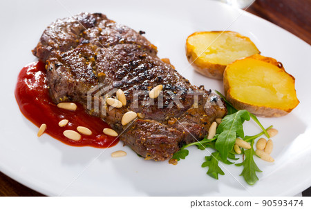 Well done roasted veal steak with ketchup, pine nuts 90593474