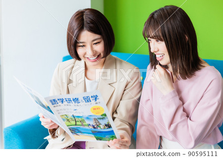 A woman looking at a language study abroad pamphlet at a cafe 90595111
