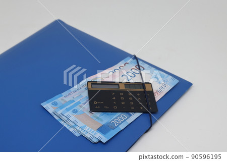 Calculator and banknotes lie on a folder for papers, financial accounting and control. Calculator and banknotes lie on a folder for papers, financial accounting and control. 90596195