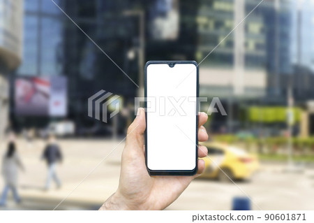 A smartphone in a hand with a blank screen against the backdrop of an urban street of the business quarter of the city. Business applications, transport, taxi, maps concept A smartphone in a hand with a blank screen against the backdrop of an urban street of the business quarter of the city. Business applications, transport, taxi, maps concept 90601871