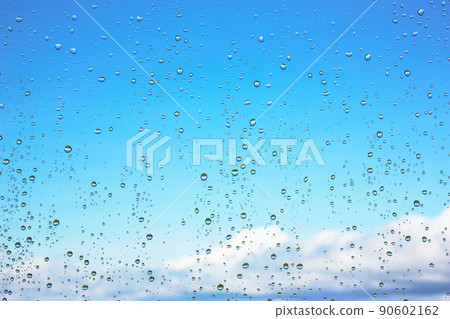 Water droplets on glass against the blue sky with clouds 90602162