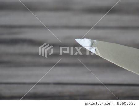 Baking soda on the tip of a metal knife on a wooden background. Baking soda on the tip of a metal knife on a wooden background. 90603553