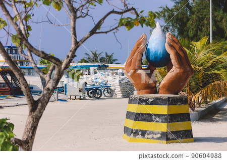 Local Monument with the Folded Hands and Blue Water Drop at the Maafushi street Local Monument with the Folded Hands and Blue Water Drop at the Maafushi street 90604988