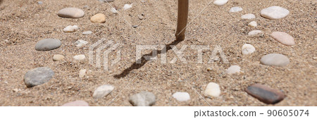 Wooden stick and pebbles on sand showing time by shadow Wooden stick and pebbles on sand showing time by shadow 90605074