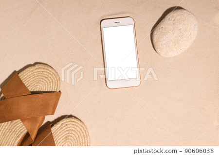 Beach background with mobile phone ,brown sandals and stone on a sandy beach in the sun. Concept: Summer vacation in a warm country. Beach background with mobile phone ,brown sandals and stone on a sandy beach in the sun. Concept: Summer vacation in a warm country. 90606038