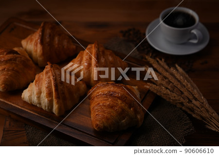 Fresh homemade butter croissant in tray decorated with wheat on wooden table. Levitation, bread bakery products cafe concept Fresh homemade butter croissant in tray decorated with wheat on wooden table. Levitation, bread bakery products cafe concept 90606610