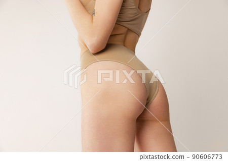 Cropped image of female buttocks in underwear isolated over grey studio background. Fitness and healthy eating Cropped image of female buttocks in underwear isolated over grey studio background. Fitness and healthy eating 90606773