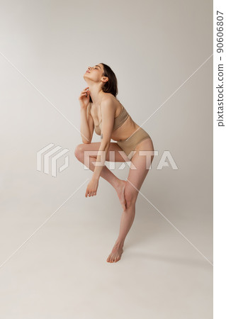 Portrait of beautiful young woman posing in beige underwear isolated over grey studio background 90606807