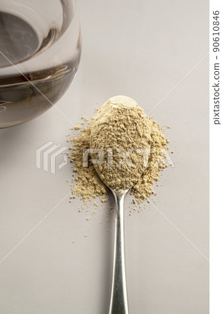 Heap of protein powder and a spoon with glass of water. Food supplements 90610846