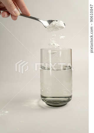Woman pours collagen powder or protein in a glass of water on a beige background. A healthy and anti aging supplement. Copy space Woman pours collagen powder or protein in a glass of water on a beige background. A healthy and anti aging supplement. Copy space 90610847