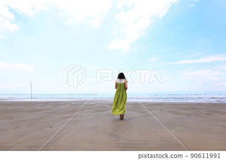 A woman walking on a sandy beach with sandals A woman walking on a sandy beach with sandals 90611991