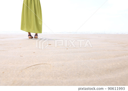 A woman walking on a sandy beach with sandals A woman walking on a sandy beach with sandals 90611993