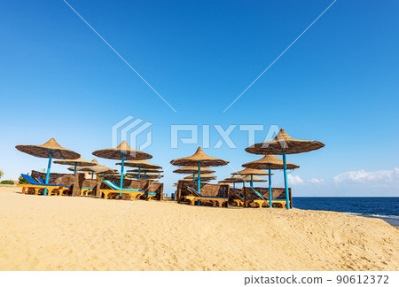 Red Sea Beach with Straw Umbrellas and Deck Chairs - Marsa Alam Egypt Africa Red Sea Beach with Straw Umbrellas and Deck Chairs - Marsa Alam Egypt Africa 90612372