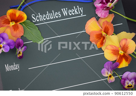 Weekly calendar blackboard with orange and purple violets on a black background 90612550