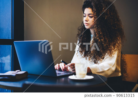 Curly female freelancer watching video vlog browsed on modern laptop computer Curly female freelancer watching video vlog browsed on modern laptop computer 90613315