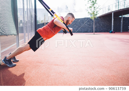 Powerful sportsman training with TRX straps 90613739