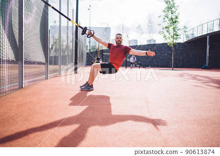 Energetic sportsman doing workout with sling trainer 90613874