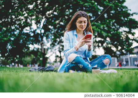 Young female blogger networking social media while installing smartphone app 90614004