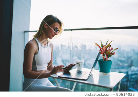 Woman watching photos on tablet in cafeteria 90614028