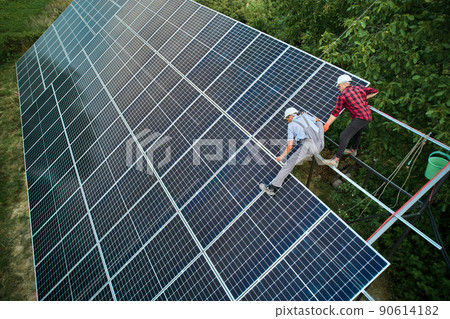 Aerial view of men technicians installing solar panels to high steel platform. Concept of alternative energy. 90614182