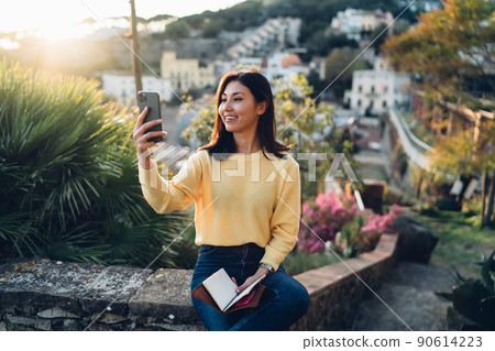 Positive Asian woman having video call on smartphone Positive Asian woman having video call on smartphone 90614223