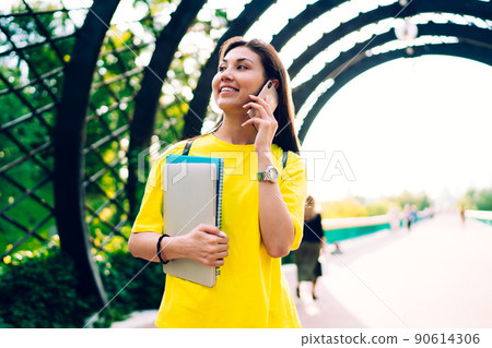 Joyful woman speaking on phone during walk Joyful woman speaking on phone during walk 90614306