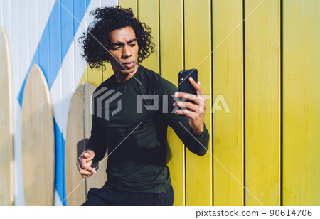 Serious man using mobile phone standing against shabby background Serious man using mobile phone standing against shabby background 90614706