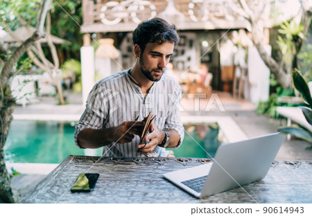Focused man with notebook and laptop sitting near swimming pool 90614943