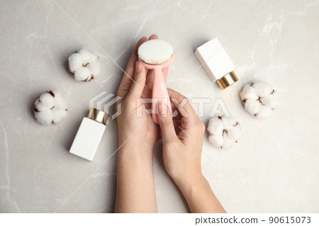 Woman with stylish face cleansing brush at light grey table, top view. Cosmetic accessory Woman with stylish face cleansing brush at light grey table, top view. Cosmetic accessory 90615073