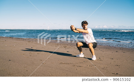 Energetic man training on seashore 90615102