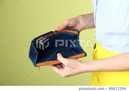 Woman showing empty wallet on light green background, closeup Woman showing empty wallet on light green background, closeup 90615104