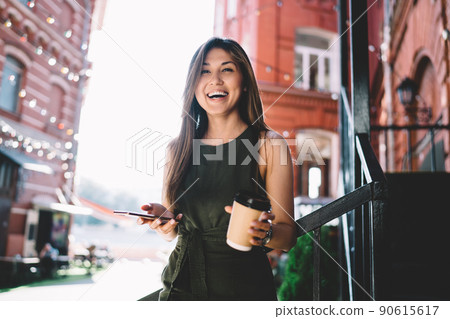 Joyful hipster girl with modern cellular technology and takeaway cup 90615617
