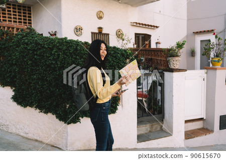 Joyful hipster backpacker reading orientation paper and smiling satisfied with solo trip journey 90615670