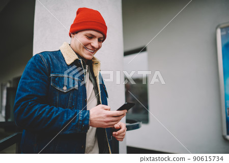 Happy man messaging on smartphone on street Happy man messaging on smartphone on street 90615734