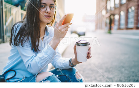 Young female blogger looking at camera using mobile phone and 4G internet 90616203