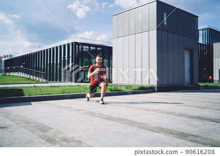 Young sportsman exercising near downtown with phone in hand Young sportsman exercising near downtown with phone in hand 90616208