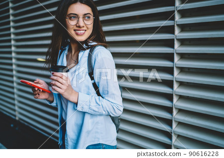 Carefree woman in optical eyewear and stylish apparel smiling at urban setting Carefree woman in optical eyewear and stylish apparel smiling at urban setting 90616228
