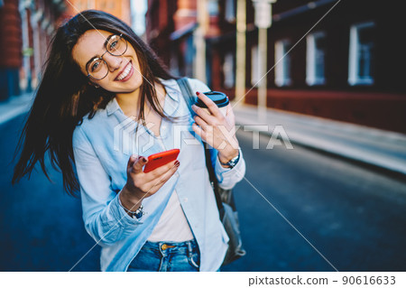 Emotional woman laughing outdoors using mobile phone at urban setting 90616633