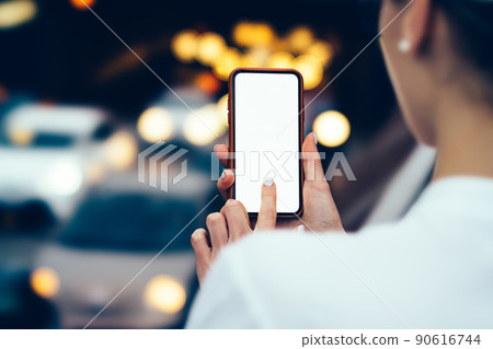 Crop faceless woman using mobile application on smartphone in city center 90616744