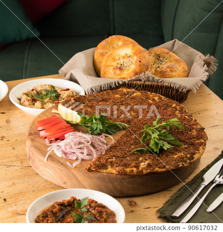 Close up shot of a lahmacun and a salad near basket of breads Close up shot of a lahmacun and a salad near basket of breads 90617032