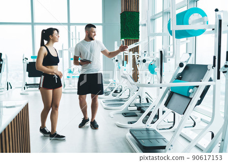 Fit trainer with woman near exercise equipment Fit trainer with woman near exercise equipment 90617153
