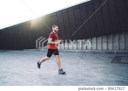 Male athlete jogging with phone during training 90617827