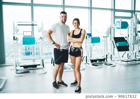 Cheerful sportsman with partner near modern gym equipment Cheerful sportsman with partner near modern gym equipment 90617832