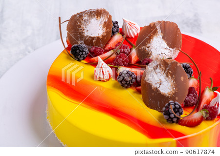 Close-up shot of a mirror glaze cake decorated with berries. 90617874