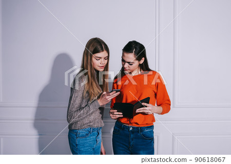 Young women surfing internet on smartphones in light room Young women surfing internet on smartphones in light room 90618067