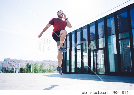 Sporty man jumping on street on sunny day Sporty man jumping on street on sunny day 90618144