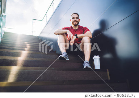 Satisfied jogger sitting near wall 90618173