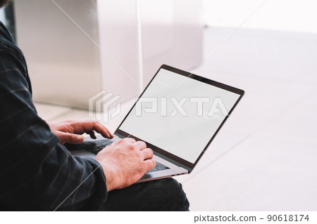 Unrecognizable man typing on keyboard of laptop with blank screen 90618174