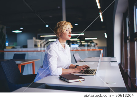 Pensive woman with laptop in modern workspace 90618204