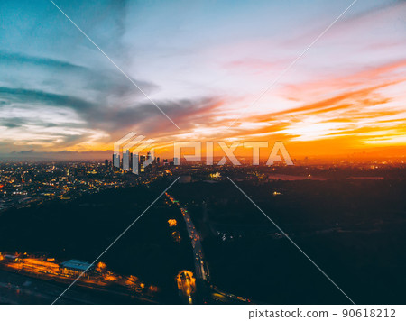 Sunset in cloudy sky over glowing city Sunset in cloudy sky over glowing city 90618212